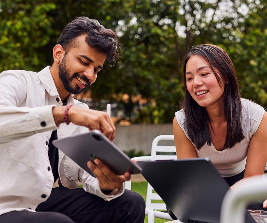 Two people seated together, looking at an iPad screen.
